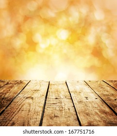 Autumn rustic template background with text space. Old vintage planked wood table in perspective on warm orange abstract bokeh - outdoor in the garden.