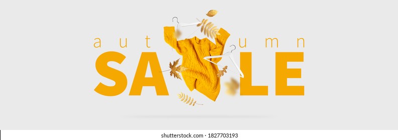 Autumn Sale Fall Shopping. Orange Flying Women's Knitted Sweater White Wooden Hangers Golden Autumn Leaves On Gray Background Creative Clothing Concept Trendy Fall Cozy Sweater Pullover Jersey Fashion