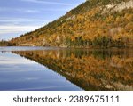 Autumn scene in Franconia Notch State Park. Colorful mirror image reflection of sky and treelined mountain on calm surface of Echo Lake in the White Mountains of New Hampshire.