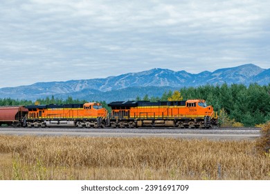 Autumn scene of a freight train pulling cargo through mountainous country close to Whitefish, Montana