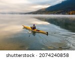 Autumn scene of kayaker paddling on Lake McDonald, Glacier National Park, Montana on a calm foggy morning