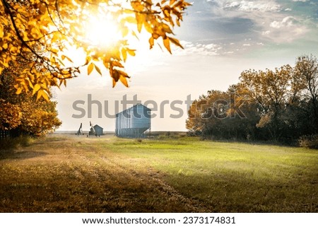 Autumn scene on a farmyard with grain silos and farm equipment during fall harvest on a prairies landscape in Kneehill County Alberta Canada.
