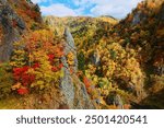 Autumn scenery of vibrant fall colors on the rocky cliffs surrounding Hoheikyo Dam 豊平峡ダム, which is located in a beautiful gorge in Shikotsu-Toya National Park, in Sapporo, Hokkaido, Japan