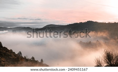 Autumn season landscape. The mountains and trees are shrouded in mist and clouds. Wide angle photo of countryside landscape in fog.