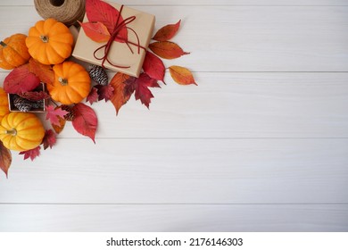 Autumn seasonal concept decoration. Autumn leaves, pumpkin and gift box on white wooden background. Thanks giving, Halloween and Autumn event decorative elements. - Shutterstock ID 2176146303