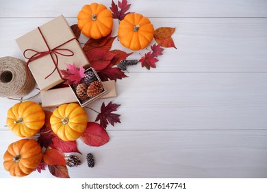 Autumn seasonal concept decoration. Autumn leaves, pumpkin and gift box on white wooden background. Thanks giving, Halloween and Autumn event decorative elements.