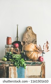 Autumn Seasonal Food Ingredients And Kitchen Utensils. Vegetables, Pumpkin, Red Apples, Canned Food, Fallen Leaves Over Rustic Wooden Chest Of Cupboard, Copy Space. Thanksgiving Dinner Preparation