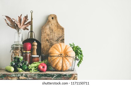 Autumn Seasonal Food Ingredients, Kitchen Utensils. Vegetables, Pumpkin, Apples, Canned Food, Fallen Leaves Over Rustic Wooden Chest Of Cupboard, Copy Space. Thanksgiving Dinner Preparation