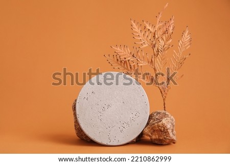 Autumn showcase made of natural wood, autumn foliage, glass brown bottle essential oil. Podium presentation cosmetics is made of wood on beige background. Minimalistic branding scene.