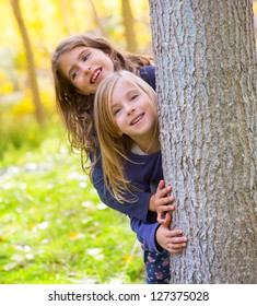 Autumn sister kid girls playing in poplar tree forest near trunk in nature outdoor