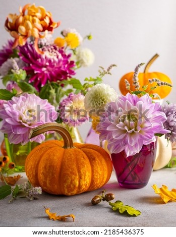 Autumn still life with bouquet of flowers and white and orange pumpkins on table. Autumn decoration for home.