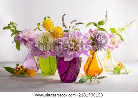 Autumn still life with bouquets of flowers in multicolored vases on table. Autumn floral decoration for home.