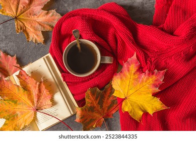 Autumn still life: Cup of hot coffee wrapped in a red knitted scarf, open book and autumn leaves on a dark background  - Powered by Shutterstock