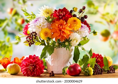 Autumn still life with garden flowers. Beautiful autumnal bouquet in vase, apples and berries on wooden table. Colorful dahlia and chrysanthemum.