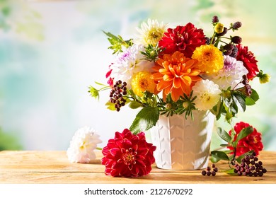 Autumn still life with garden flowers. Beautiful autumnal bouquet in vase on wooden table. Colorful dahlia, chrysanthemum and berries. - Powered by Shutterstock