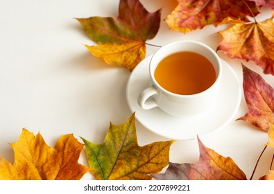 Autumn Still Life. A Mug Of Hot Tea Among Autumn Leaves On A White Background.