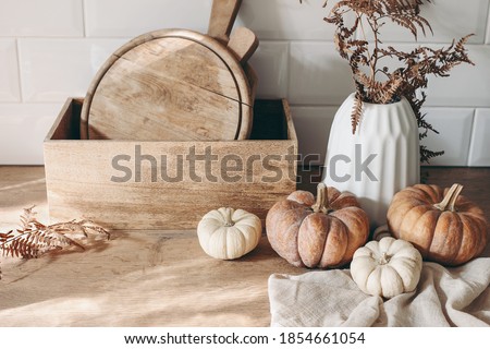 Autumn still life. White and orange pumpkins with wooden chopboards in sunlight kitchen. Dry fern in vase. Kitchen. Wooden table background with linen napkin. Thanksgiving, Halloween concept. Stock photo © 
