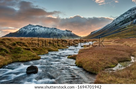 The Autumn Sun Sets the Sky on Fire and Makes a Glaciel River Glow on the Snaefellsjokull Peninsula with the Snaefellsjokull Volcano Looming Large