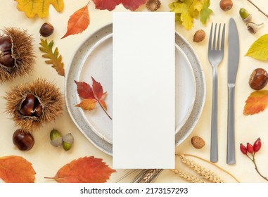 Autumn Table Place With Colorful Leaves And Blank Menu Card Top View. Mockup Of Fall Vertical Card On Light Yellowtable, Flat Lay, Copy Space. Harvest, Halloween And Thanksgiving Season