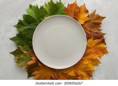 Autumn Table Setting, Green, Red And Yellow Fallen Maple Leaves And An Empty Plate, Thanksgiving Holiday