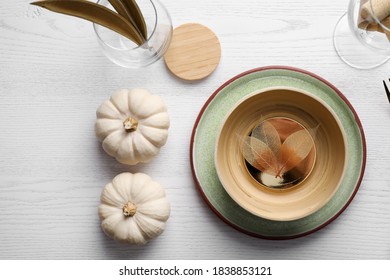 Autumn table setting with pumpkins on white wooden background, flat lay