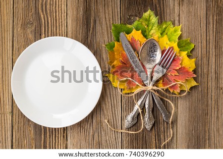 Autumn Table setting. Thanksgiving dinner plate with fork, knife and leaves on rustic wooden table background. Top view, copy space, place for text.