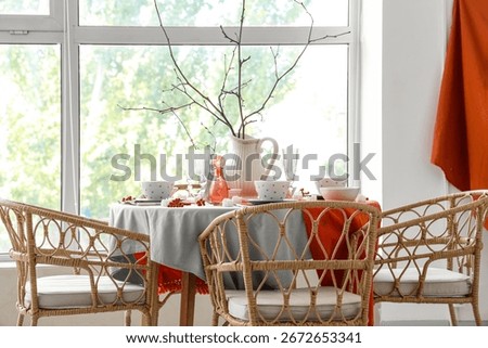 Autumn table setting with tree branches and berries in light dining room