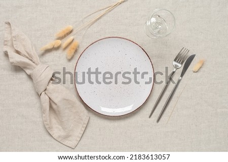 Autumn table setting. A white plate, cutlery and dry grass lagurus on a beige linen textile background. Top view, flat lay. Selective focus. Stock photo © 