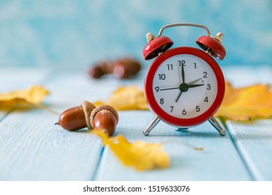 Autumn time change concept - red alarm clock on wood background, copy space
