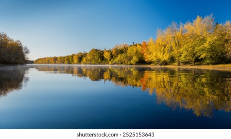 Autumn trees reflected in calm water with clear blue sky - Powered by Shutterstock