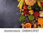 Autumn vegetable preparation dinner background. Food background with organic fresh farm raw veggies, pumpkin, corn, fruits, mushrooms, salad leaves, greenery, Ingredients for cooking with copy space.