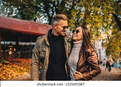 Autumn walk. Couple. Love. Man and woman in warm casual clothes are talking and smiling while walking in the park - Powered by Shutterstock