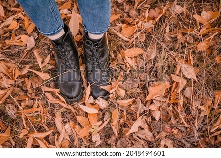 Autumn walk in the red foliage. Top view. Feet in jeans and shoes on leaves. Atmosphere. A place for text. High quality photo