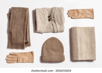 Autumn warm clothes flat lay, knitted hat, wool scarf and suede gloves, beige sweater. Women knit wear for cold weather in autumnal season. Top view.