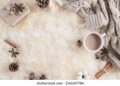 Autumn Or Winter Composition. Gift Box Coffee Cup, Cinnamon Sticks, Anise Stars, Beige Sweater With Knitted Blanket On Cream Color Gray Fluffy Background. Flat Lay Top View Copy Space.