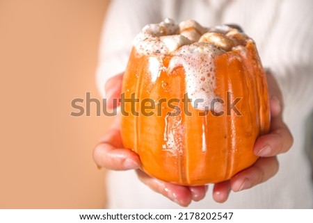 Autumn, winter drinks, Beverage ideas for Christmas, Thanksgiving, Halloween. Girl hands with drink spicy pumpkin latte, hot chocolate, with whipped cream, marshmallow, pumpkin spice
