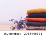 Autumn, winter season knitwear. Woolen sweaters and dried lavender for protection from moth. Knitted warm wool clothes. Stack of warm knitted clothes with lavender. Home wardrobe with winter clothes.
