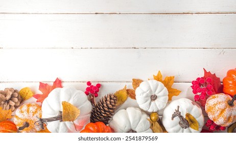 Autumnal arrangement with white and orange pumpkins, autumn leaves, pine cones, and red berries on a white wooden surface, evoking a festive fall ambiance - Powered by Shutterstock