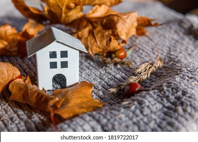 Autumnal Background. Toy House And Dried Orange Fall Maple Leaves On Grey Knitted Sweater. Thanksgiving Banner Copy Space. Hygge Mood Cold Weather Concept. Hello Autumn With Family.