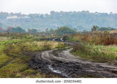 autumnal foggy morning rustic lansdcape with dirt road in the foreground and small buildings on hill in the background - sharp due to focus stacking technique
