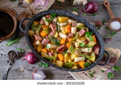 Autumnal Stew With  Root Vegetables And  Black Salsify Turnip  Sugar Snap Peas And  Potatoes Cooked With Smoked Pork Meat And Served On Rustic Wooden Table Overhead View