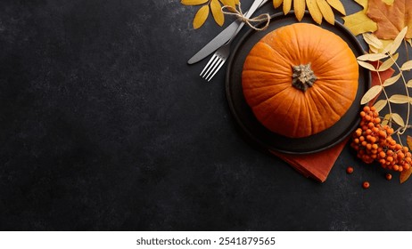 Autumnal table setting with a pumpkin, stainless steel utensils, fall leaves, orange berries, and rustic napkin on a textured slate surface, perfect for Thanksgiving dinner - Powered by Shutterstock