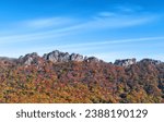 Autumnal view of red maple trees with peak and rock cliff of Naejangsan Mountain against blue sky near Jeongeup-si, South Korea
