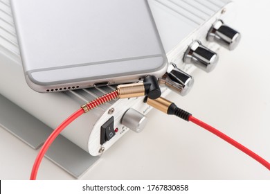 AUX cable connected between smartphone and mini amplifier. Cable for stereo input and output. - Shutterstock ID 1767830858