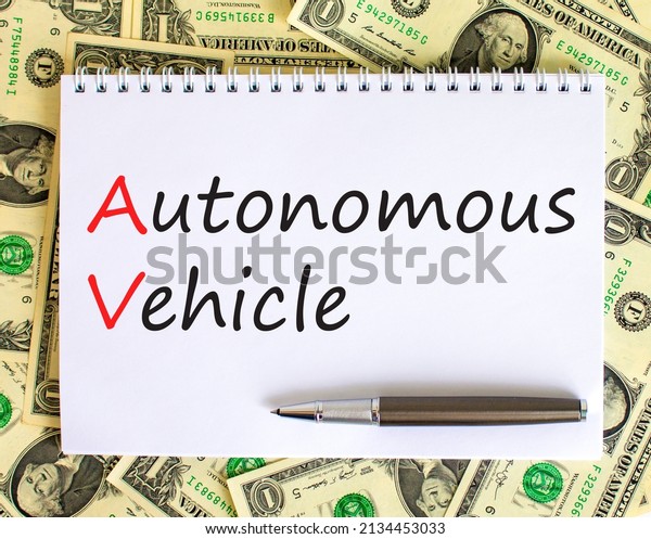 AV autonomous vehicle symbol. Concept words AV\
autonomous vehicle on white note on beautiful background from\
dollar bills. Metallic pen. Business technology AV autonomous\
vehicle concept. Copy space.
