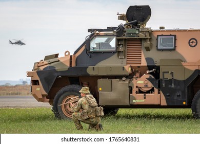 Avalon, Australia - February 27, 2015: Australian Army Soldier With A Bushmaster Armored Personnel Carrier (APC) And An Army Eurocopter Tiger Helicopter.