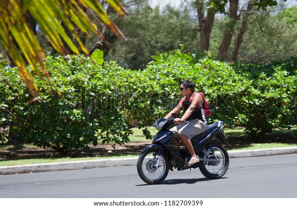 AVARUA, COOK ISLANDS - FEBRUARY 5,\
2009: Young Man Riding Motor Bike in Avarua, Cook\
Islands