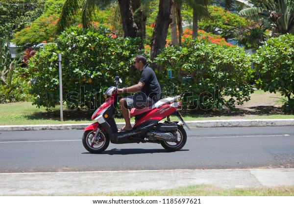 AVARUA, COOK ISLANDS - FEBRUARY 5, 2009: Man\
Riding Motor Bike in Avarua, Cook\
Islands