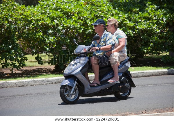 AVARUA, COOK ISLANDS - FEBRUARY\
5, 2009: Mature Couple Riding Motor Scooter in Avarua, Cook\
Islands.