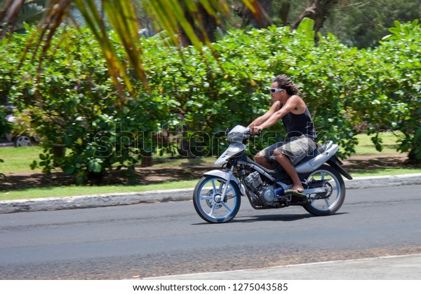 AVARUA, COOK ISLANDS - FEBRUARY 5,\
2009: Young Man Riding Motor Bike in Avarua, Cook\
Islands.